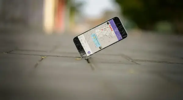 Zgubiony telefon z pękniętym ekranem leży na chodniku. Na wyświetlaczu widać wiadomość: "Did you just break up w/ me?".
