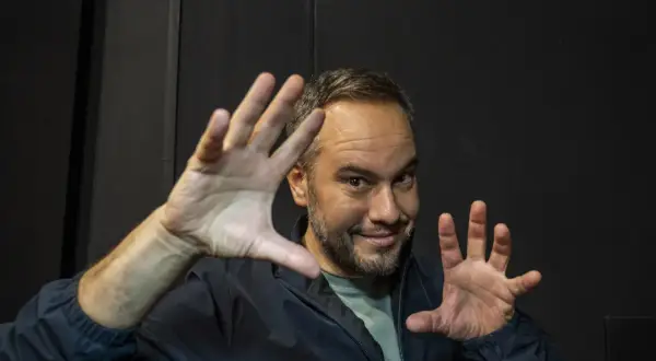 Jorge Blass Zaragoza, ilusionista, sonríe con las manos extendidas, listo para un truco.