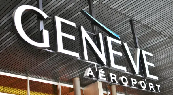 Napis "GENEVE AEROPORT" na tle nowoczesnej architektury, symbolizujący jedne z wielu lotnisk w Szwajcarii.