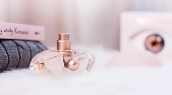 Eleganckie perfumy Kenzo World w szklanym flakonie z złotym detalem, otoczone miękkim futerkiem i książką o urodzie.