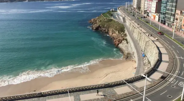 Una de las 10 mejores playas de A Coruña, con arena dorada, mar turquesa y un paseo marítimo con edificios modernos.