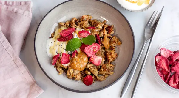 En skål med granola, yoghurt, jordnötssmör, torkade jordgubbar och mynta. En perfekt nyttig frukost för en bra start på dagen.