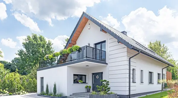 Nowoczesny biały dom z balkonem i zielenią. Idealne miejsce na realizację darmowe projekty domów.