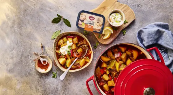 Herzhaftes Gulasch mit Kartoffeln und Paprika, perfekt zum Schmoren lassen. Daneben ein Becher Schmalz und Gewürze.