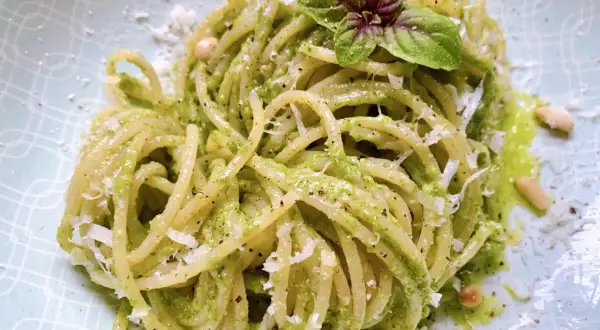 Ein Teller mit köstlichen Pesto Nudeln, garniert mit frischem Basilikum und Pinienkernen.