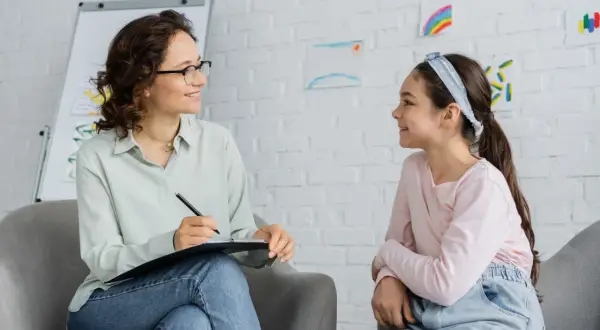 Psycholog rozmawia z dziewczynką, która ma zespół Aspergera. Czy asperger to autyzm? Dzieci rysują na ścianie.
