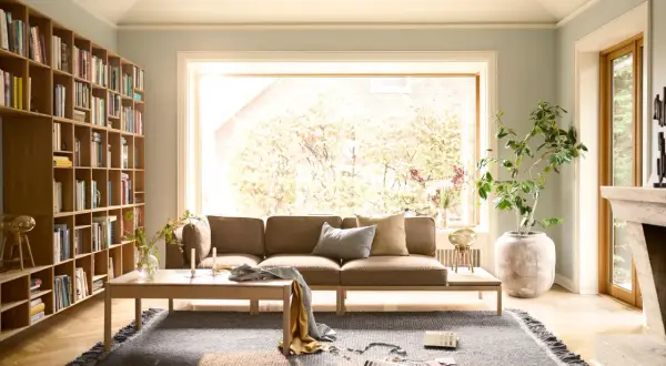 Gemütliches Wohnzimmer mit braunem Sofa, Bücherregal und Kamin. Tolle Sofa Ideen für wenig Platz, die Gemütlichkeit schaffen.
