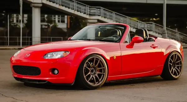 Mazda MX-5 rouge rutilante, parfaite pour un jeune permis rêvant de sa première voiture sport.