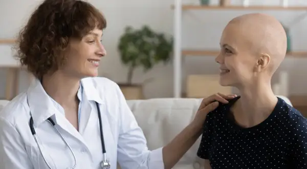 Ärztin tröstet Patientin, die ihre Haare wegen Chemotherapie verloren hat. Hoffnungsvolles Gespräch über die Chemotherapie Dauer.