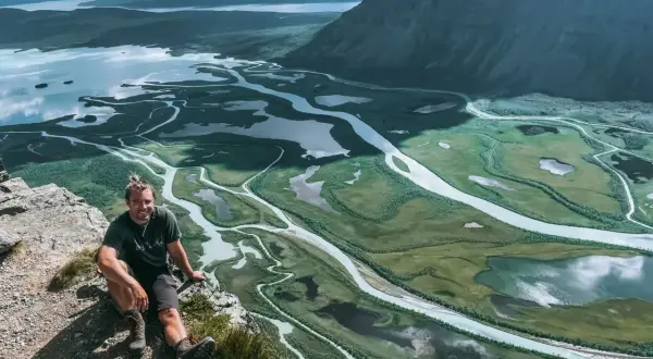 Man vilar på en klippa med utsikt över Sarek nationalparks meandrande vattendrag och fjällandskap.