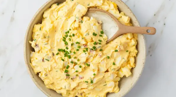 Kremowa pasta jajeczna z jogurtem, posypana szczypiorkiem, w ceramicznej misce. Idealna na kanapki.