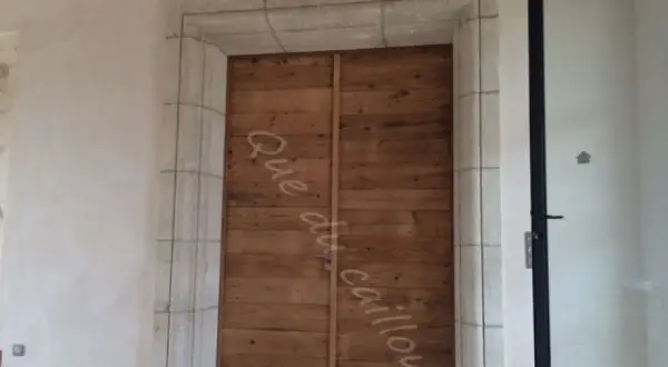 Un encadrement de porte en pierre, avec une couleur différente de la porte en bois brut.