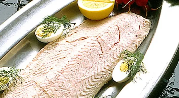 En vacker inkokt lax på ett silverfat, garnerad med ägg, citron och dill. Perfekt för en svensk sommarmåltid.