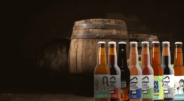 Bottiglie di birra artigianale davanti a botti di legno, un'atmosfera da keller pub.