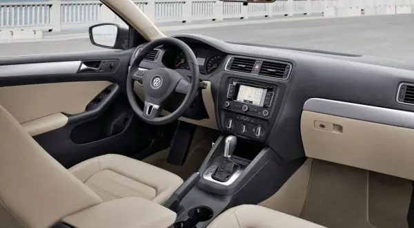 Wnętrze VW Jetta MK6 z jasną tapicerką, nawigacją i automatyczną skrzynią biegów.