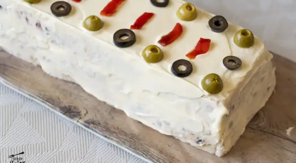 Pastel frío de atún decorado con aceitunas y pimientos rojos.