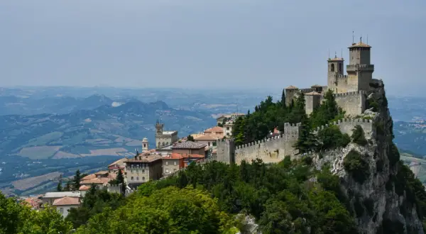 San Marino na terytorium Włoch, z górującymi wieżami i kamiennymi murami, wznosi się dumnie na skalistym szczycie, otoczone zielonymi wzgórzami.