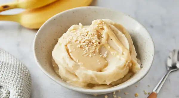 Cremiges italienisches Bananeneis mit Karamellsauce und gehackten Nüssen, garniert mit frischen Bananen.