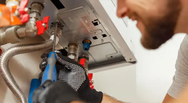 Tecnico con guanti lavora su caldaia Baxi in blocco, cercando di sbloccarla con un cacciavite.