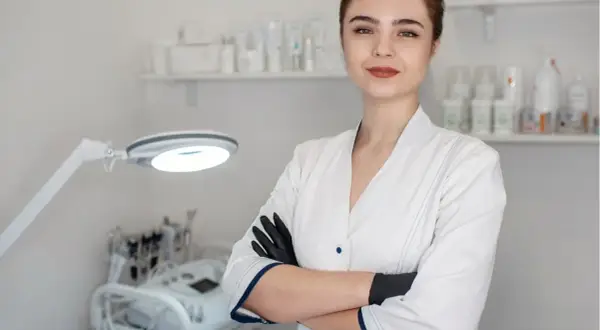 Młoda kosmetolog w gabinecie, gotowa do zabiegu. W tle sprzęt i kosmetyki.