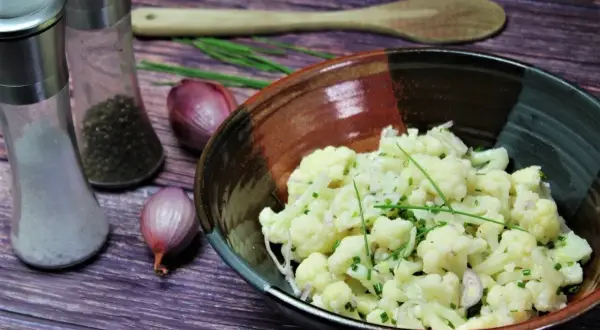Leckerer gekochter blumenkohlsalat rezepte mit Schalotten und Schnittlauch. Daneben Salz- und Pfefferstreuer.