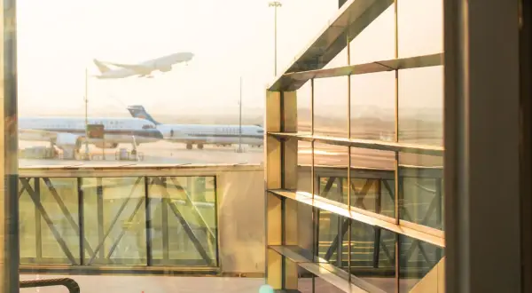 Flugzeuge starten und landen am Flughafen. Ein Flugzeug hebt ab, während andere am Gate warten. Gut, dass ich weiß, wie viel eher am Flughafen sein muss.