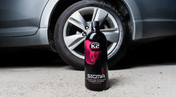 Butelka preparatu K2 Sigma Pro do pielęgnacji opon, stojąca obok koła samochodu. Płyn pomoże Ci zadbać o to, jak przechowywać opony, by służyły dłużej.