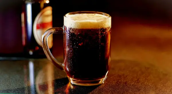 Chłodny, ciemny lager z gęstą pianką w szklanym kuflu, obok butelki.