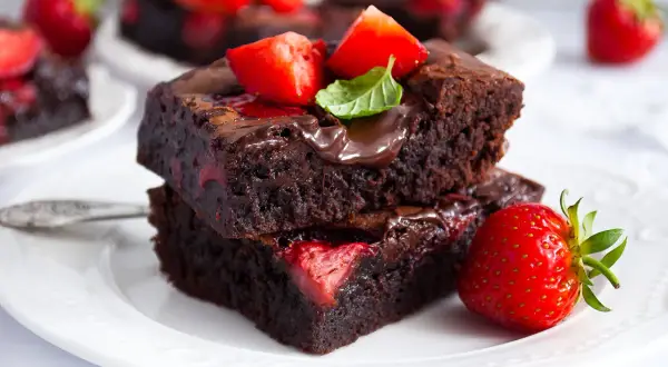 Pyszne brownie z truskawkami, polane czekoladą i ozdobione świeżymi owocami. Idealne na deser.