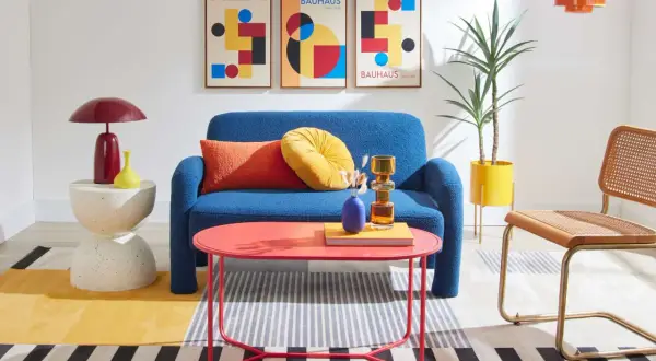 A living room showcasing bauhaus design examples: blue sofa, geometric art, and colorful accents.