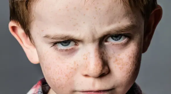 Zmarszczone brwi i spojrzenie chłopca z piegami sugerują problemy z zachowaniem.