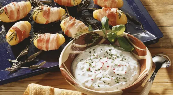 Leckere Kartoffeln im Speckmantel mit Kräutern und einem Dip.
