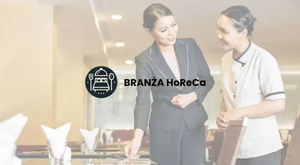 Dwie kobiety w restauracji, symbolizujące branżę HoReCa, przygotowują stolik.