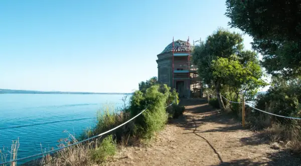 Sentiero panoramico verso un edificio storico sull'isola Bisentina. La visita è un'esperienza suggestiva tra natura e storia.