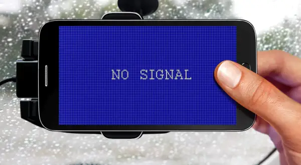 Smartfon w uchwycie samochodowym pokazuje komunikat "NO SIGNAL". Problem z GPS w deszczowy dzień.