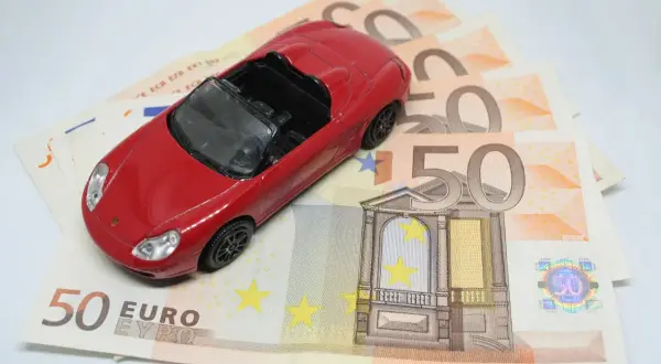 Czerwony samochodzik na banknotach 50 euro. Koszt zakupu auta i podatek PCC-3.