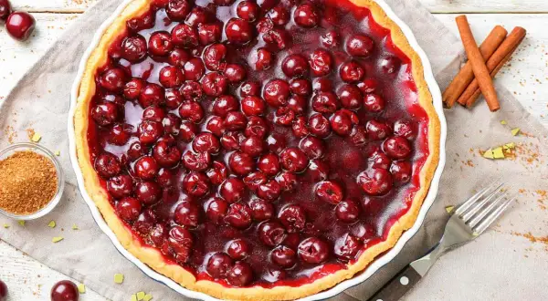 Une délicieuse tarte aux cerises, garnie de fruits rouges brillants et d'une croûte dorée. Parfaite pour un dessert gourmand.
