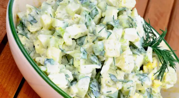 Kartoffelsalat mit Joghurt, Eiern und Gurken, garniert mit Dill. Ein leichter und erfrischender Salat.