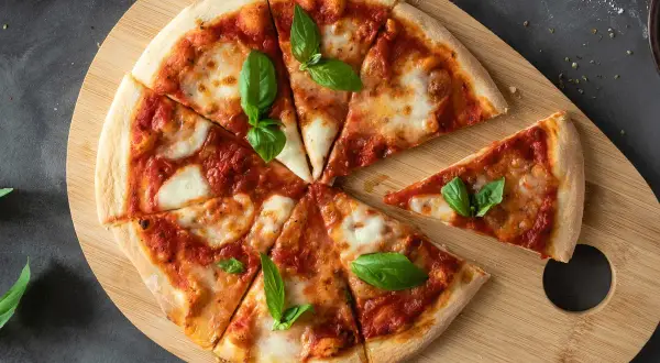Margherita pizza na drewnianej desce, idealna na szybki przepis na ciasto do pizzy. Świeża bazylia dodaje aromatu.