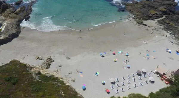 Vista aérea de la playa Paxariñas con gente disfrutando del sol y el mar.