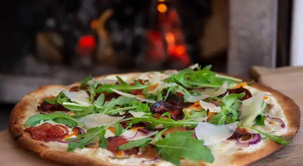 Pizza bianco med salami, ruccola och parmesan. En läcker pizza som precis kommit ut ur ugnen.