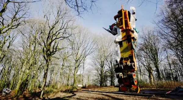 Im tony cragg skulpturenpark ragt eine bunte, auf dem Kopf stehende Konstruktion aus Metall und Stoff in den Himmel, umgeben von kahlen Bäumen.