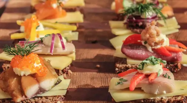 Reihe von appetitlichen Smørrebrød mit Fisch, Kaviar und Gemüse – perfektes schnelles Fingerfood für jeden Anlass.