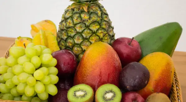 Koszyk pełen owoców: ananas, mango, winogrona, jabłka, śliwki, kiwi, awokado i karambola. Naturalna fruktoza w najlepszym wydaniu.