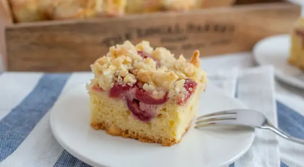 Ein Stück Kirsch-Streuselkuchen auf einem Teller, bereit zum Genießen. Dieses Streuselkuchen Rezept ist ein Klassiker.