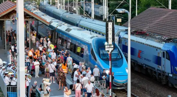Tłum ludzi na peronie czeka na pociąg Pendolino. Widoczne są różne trasy kolejowe i nowoczesne składy.