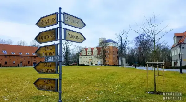 Zamek Topacz: drogowskaz wskazuje drogę do muzeum, oficyny, sali balowej, kolumnowej i kominkowej. Atrakcje czekają!