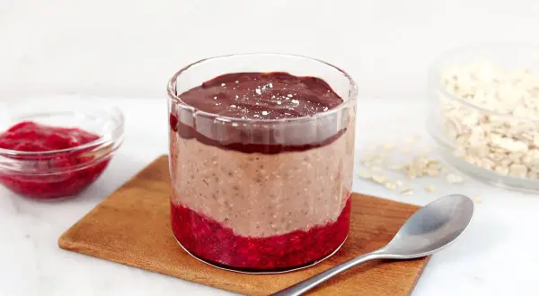 Choklad overnight oats med hallon och en sked redo att avnjutas.