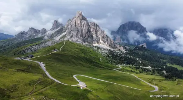 Kręta droga na Passo Giau w Dolomitach, otoczona zielonymi wzgórzami i skalistymi szczytami.