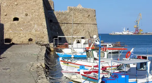 Port w Heraklionie, Kreta. Wrzesień, idealna temperatura na rejs. W tle twierdza, łodzie rybackie i dźwig portowy.